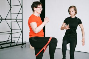 Personal trainer guiding a woman with resistance band exercise in a gym setting.