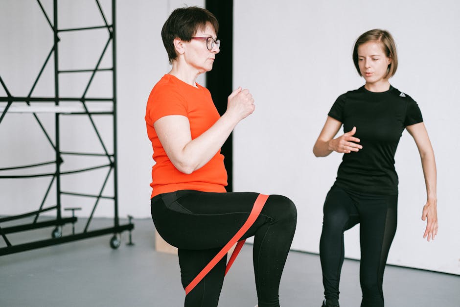 Personal trainer guiding a woman with resistance band exercise in a gym setting.